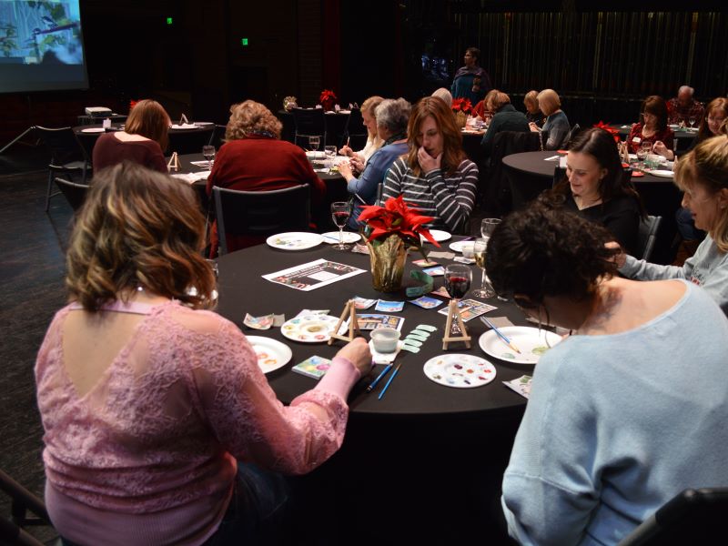 Participants of the Festival of Trees special event, Watercolor and Wine, paint their designs on the Monfort Concert Hall stage.