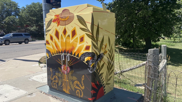 Utility cabinet wrapped with artwork inspired by Greeley legend Rattlesnake Kate, with images of a snakeskin dress, sunflower, and cowboy hat