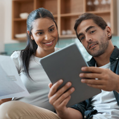 Young Hispanic couple viewing information on an iPad.
